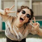 selective focus photography of jolly woman using peace hand gesture